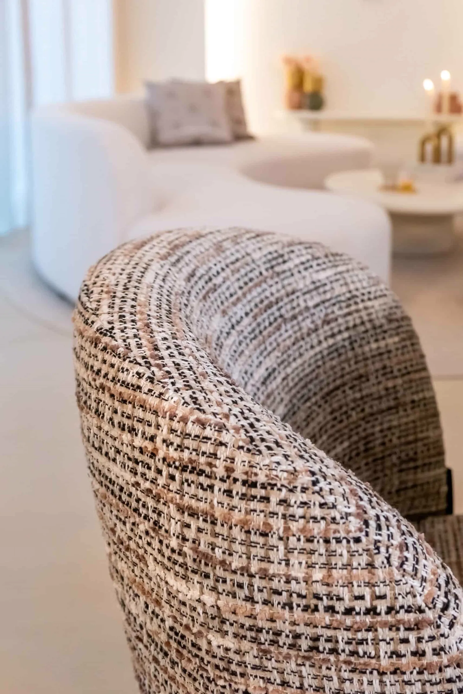 Nahaufnahme der Armlehne des Esszimmerstuhls Elvi trendy nature brandschutz mit gewebter Textur, mit einem Sofa im Hintergrund - Richmond Interiors