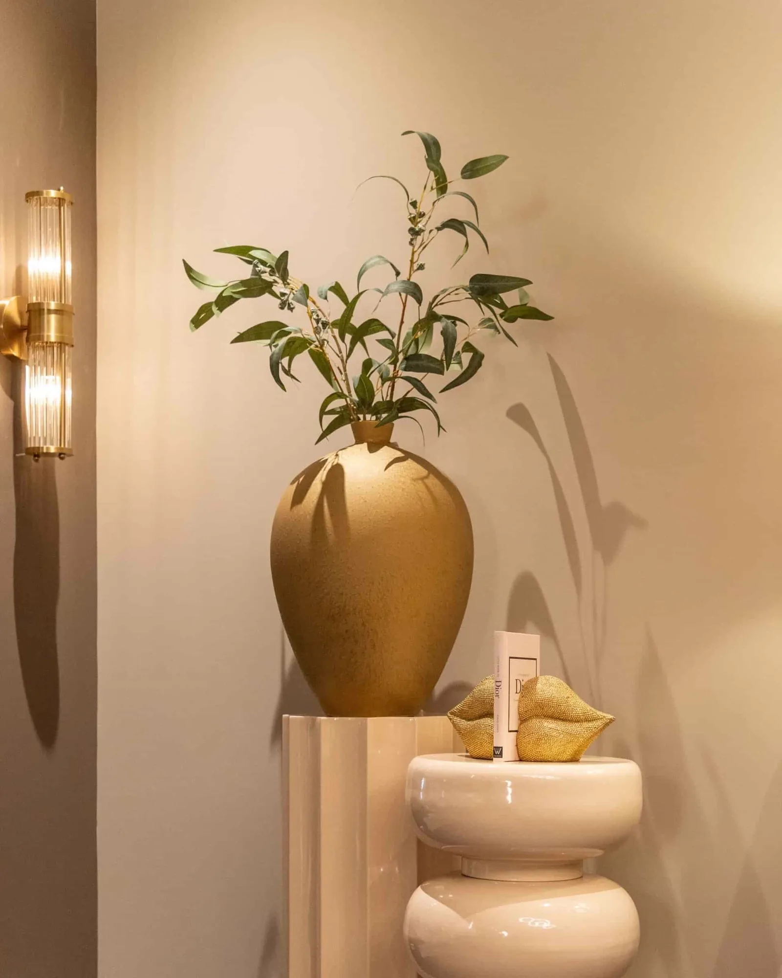 Wandleuchte Lyan brushed gold in einem Interieur mit beiger Wand und dekorativen Vasen - Richmond Interiors