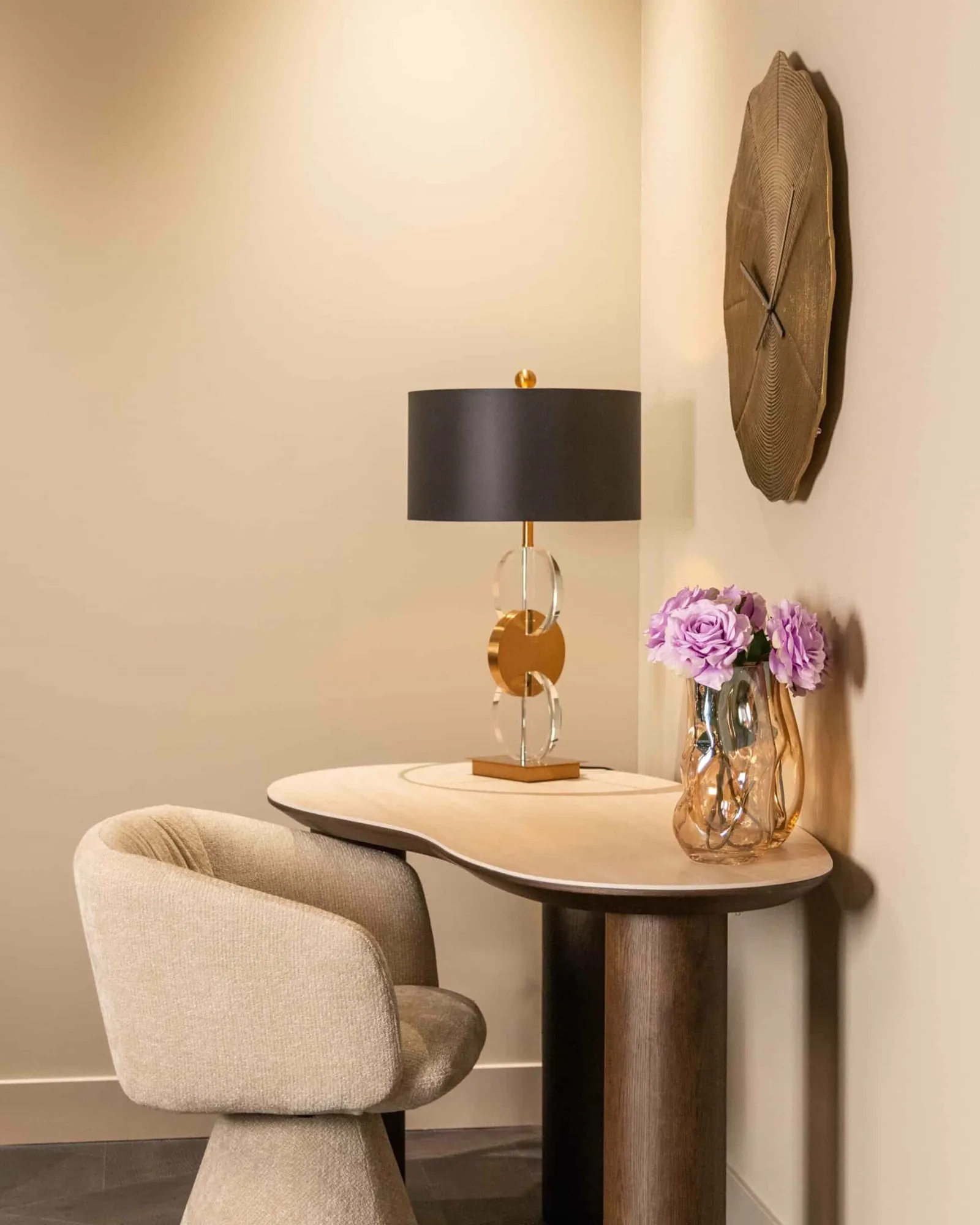 Esstuhl Madeline cream unicorn swivel steht in einer Ecke neben einem Tisch mit einer Lampe und einer Vase mit lila Blumen - Richmond Interiors