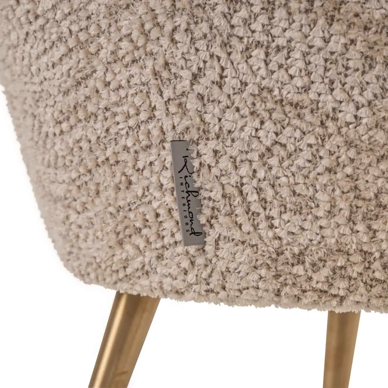 Detail des Lounge Sessel Charly lovely beige kids, mit Nahaufnahme des beigefarbenen Stoffes und einem goldenen Bein - Richmond Interiors