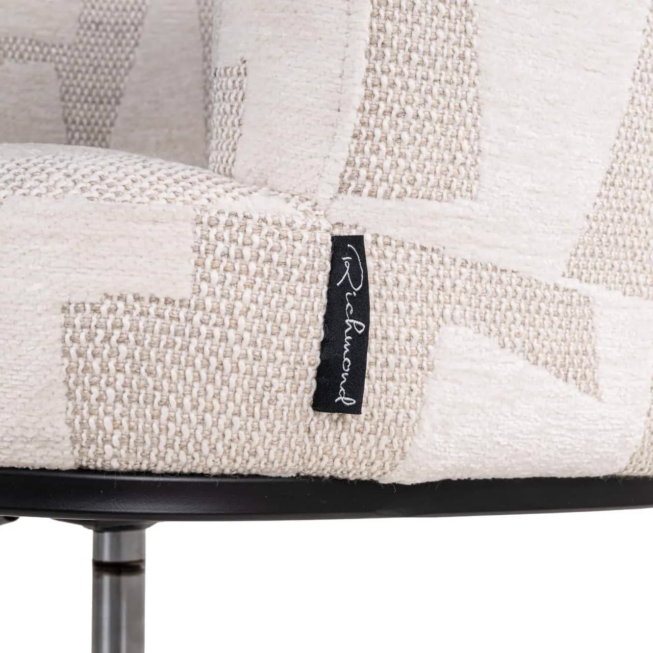 Detailaufnahme der beigefarbenen Polsterung des Esstuhls Rochenne, mit einem schwarzen Richmond Interiors Etikett