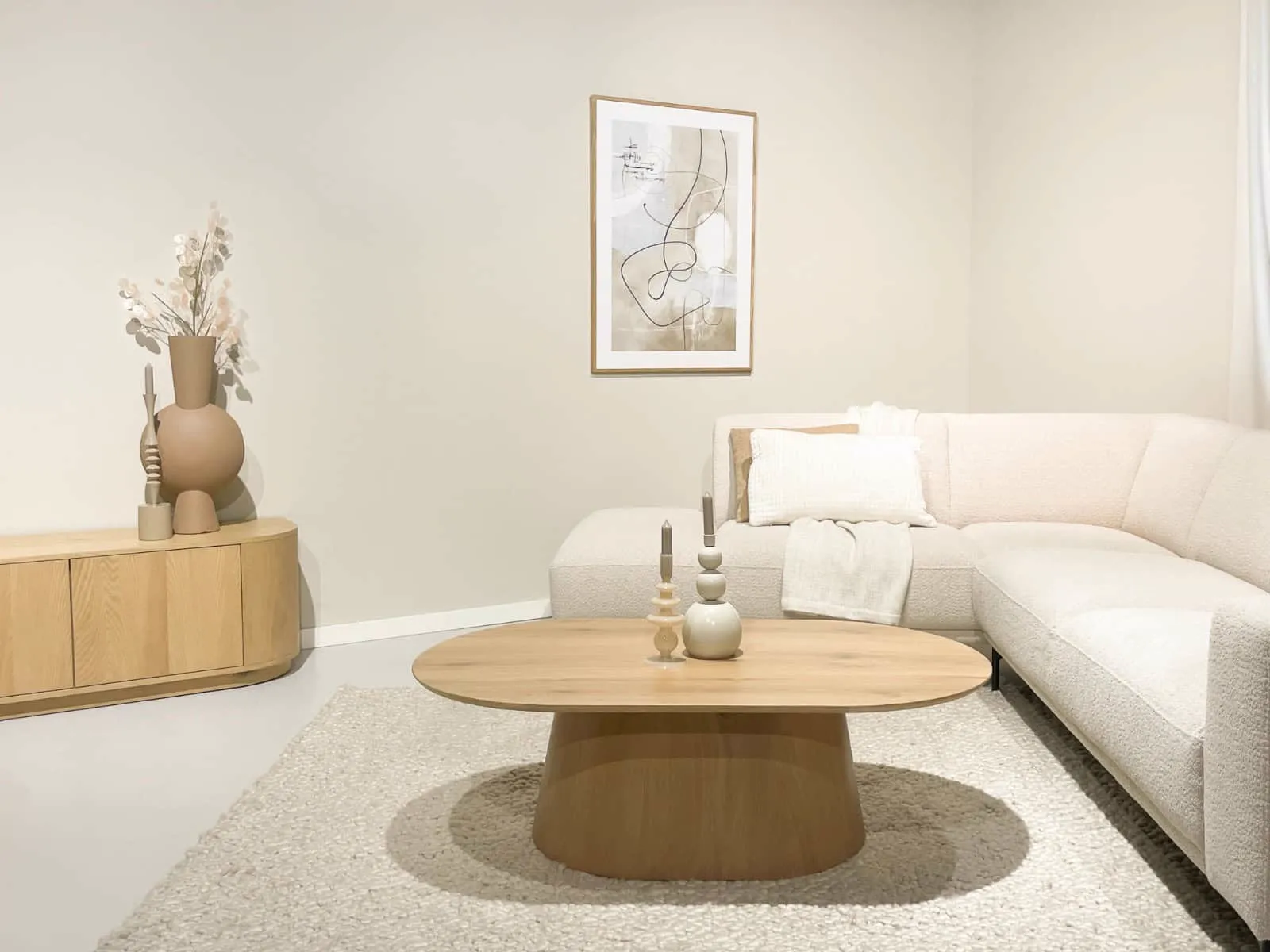 Der Novero ovale Couchtisch in einem hellen Wohnzimmer mit beigem Sofa und Teppich - Livingfurn