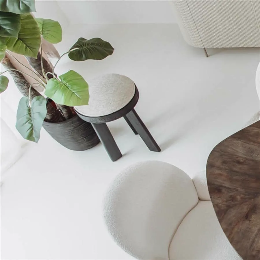 Der Ossana Hocker rund 40 cm in einem hellen Wohnzimmer mit Pflanze und weißem Stuhl - Tower Living