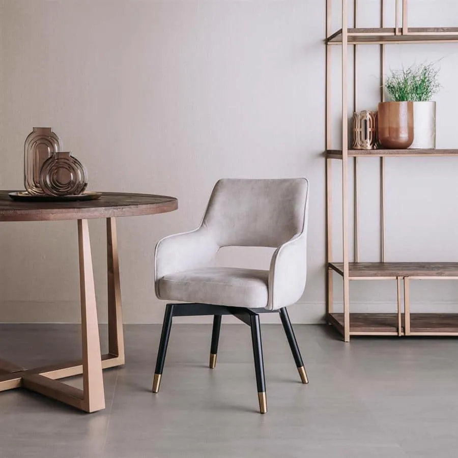 Der Lenno Sessel, Stoff Adore 11 Beige, steht in einem modernen Wohnzimmer neben einem runden Tisch und einem offenen Regal - Tower Living