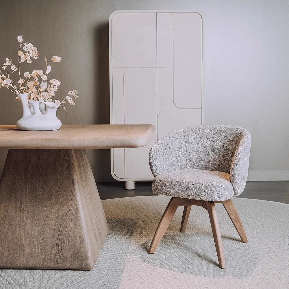Der drehbare Brescia Sessel in Puente 06 Beige White Stoff steht auf einem hellen Teppich neben einem Holztisch - Tower Living