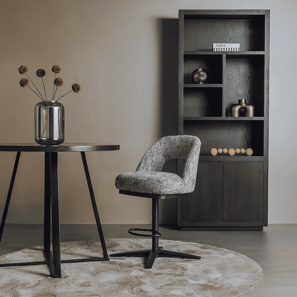 De Caldes Barstoel - fabric Ted 8 white-grey (draaibaar) staat in een moderne woonkamer bij een ronde tafel en donkere kast - Tower Living
