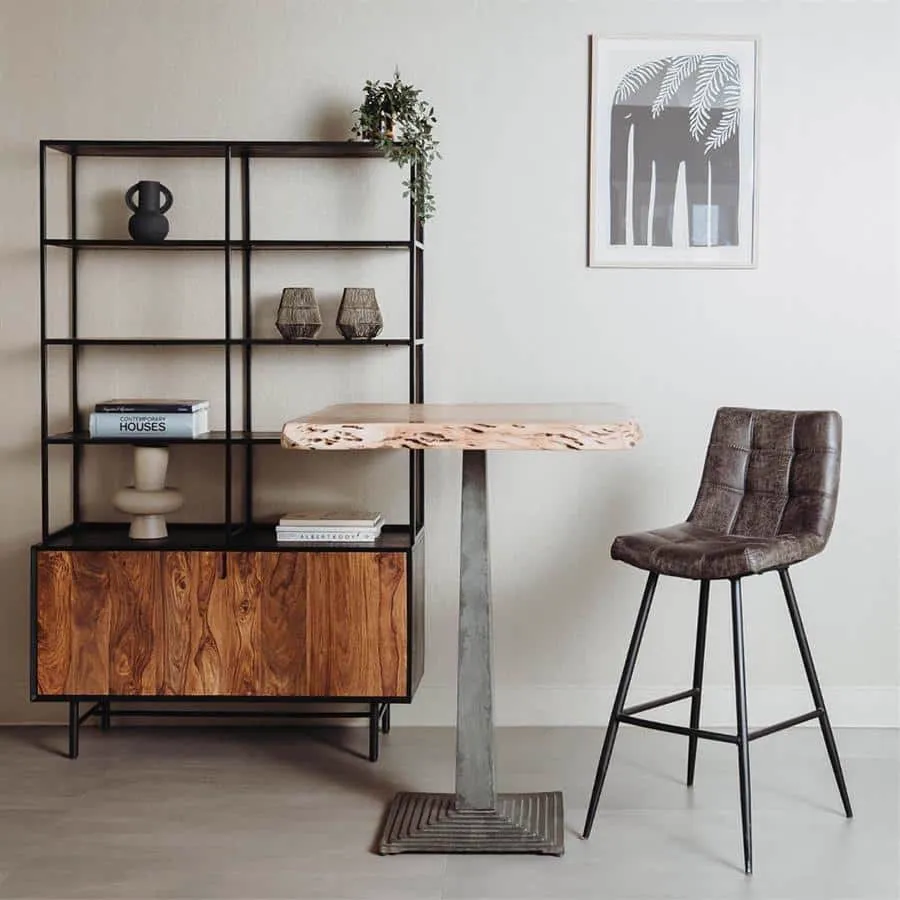 De Navarra Barstoel - fabric Antracite staat in een moderne woonkamer naast een houten bartafel en een open kast - Tower Living