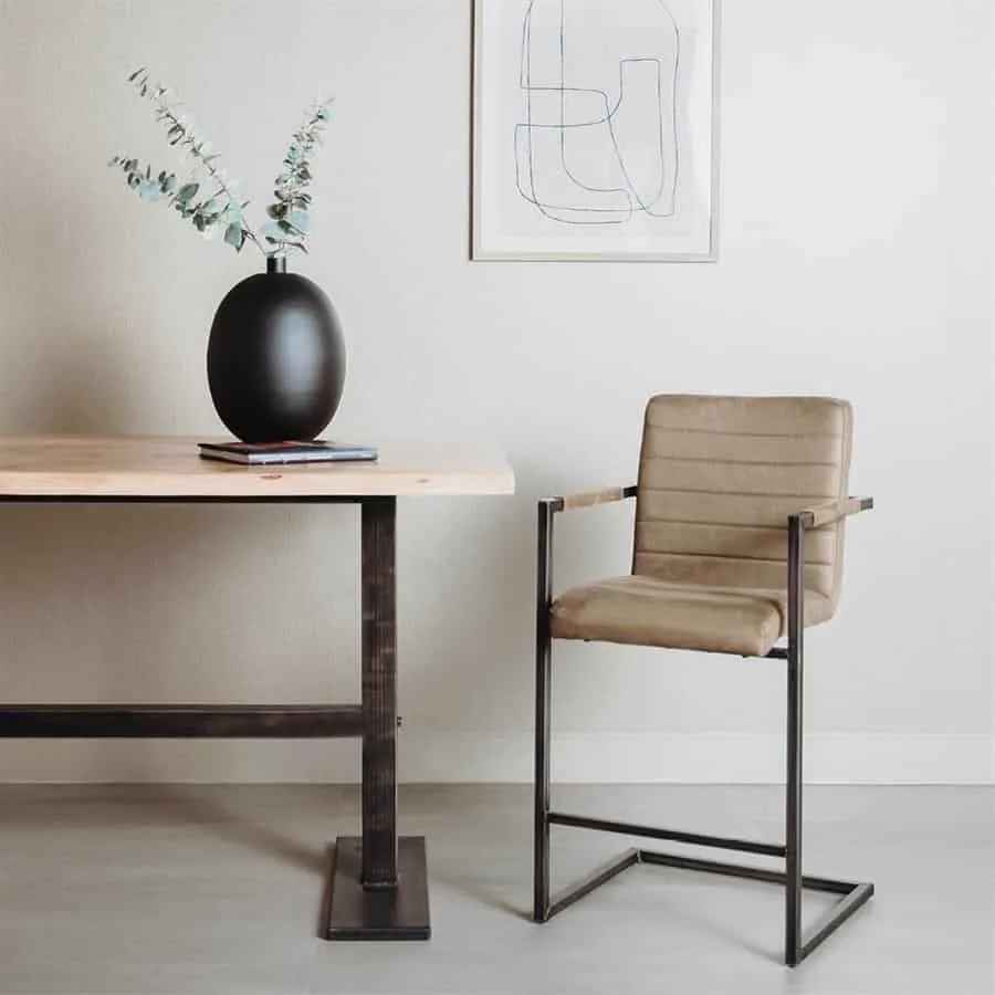 Rocca barstoel in bull green met metalen frame, in een studio-opstelling met een houten tafel en vaas - Tower Living