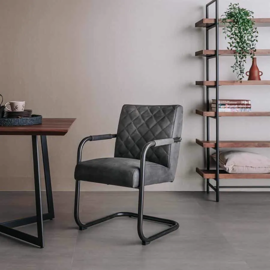 Der Civo Sessel - Bull Anthrazit steht in einem modernen Wohnzimmer neben einem Holzesstisch und einem offenen Wandregal - Tower Living
