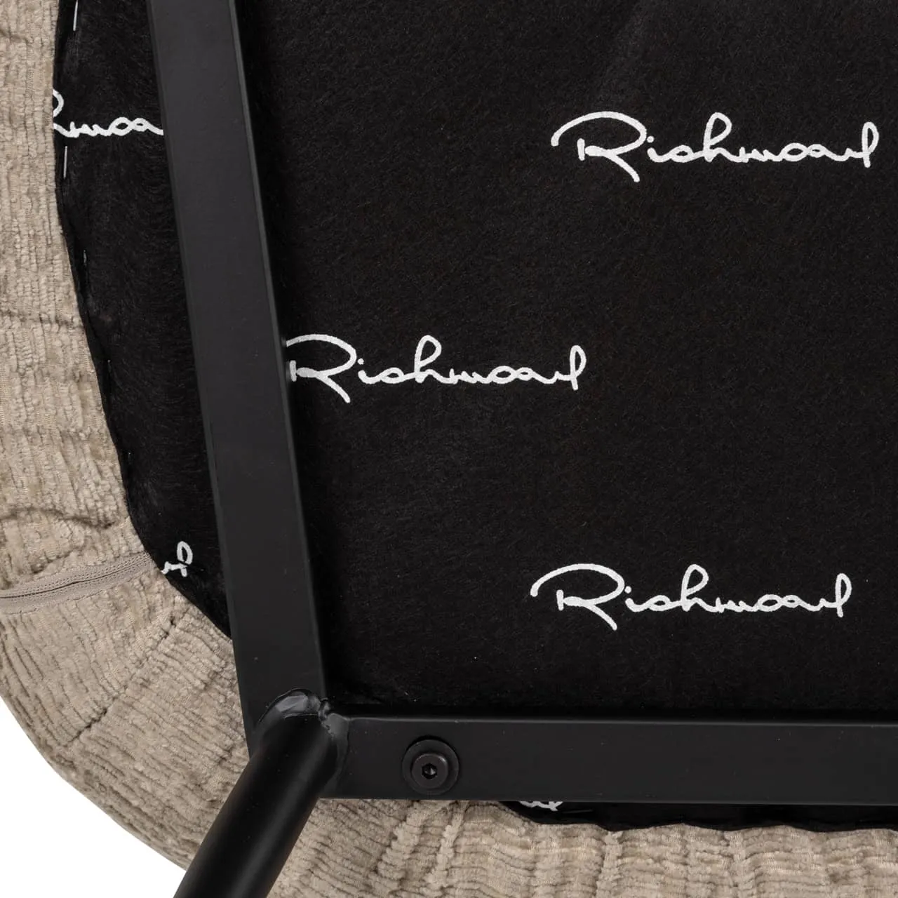 Nahaufnahme der Unterseite des Esszimmerstuhls Xandra mit dem Richmond Interiors Logo auf dem schwarzen Stoff