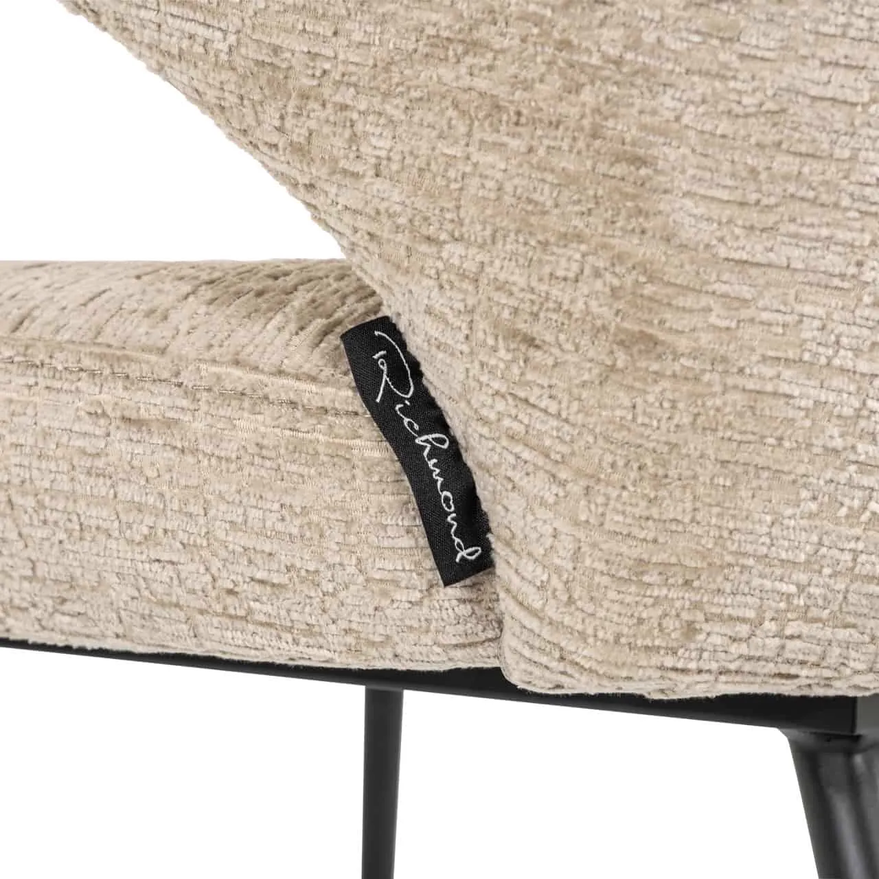 Nahaufnahme des Esszimmerstuhls Xandra, mit Fokus auf das beige Gewebe und das Richmond Interiors Etikett