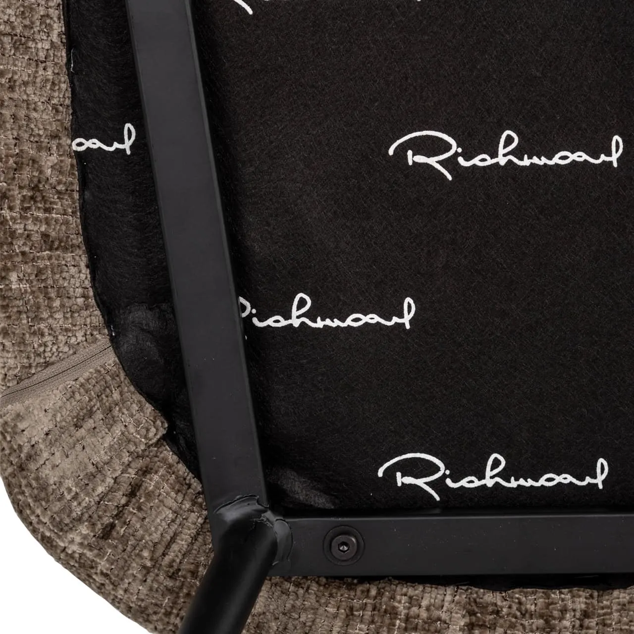 Detail der Unterseite des Esszimmerstuhls Xandra niagara stone fire retardant mit Blick auf die schwarzen Metallbeine und das Richmond Interiors Logo