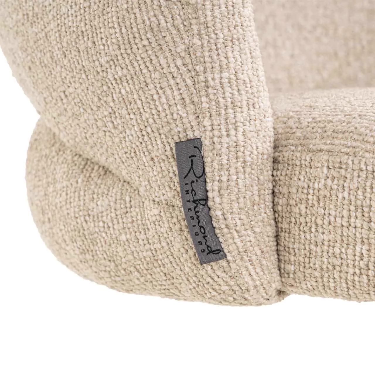 Close-up van de textuur en het merklabel van de beige stoffen eetkamerstoel Zendaya biscotti swivel fire retardant - Richmond Interiors