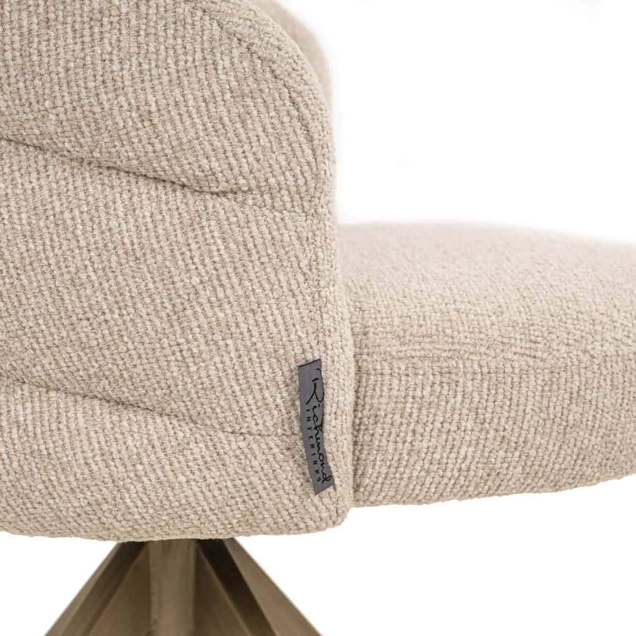 Detail des Esszimmerstuhls Zendaya Biskotti Drehbar Brandschutz, mit Fokus auf den Stoff und das Markenetikett - Richmond Interiors
