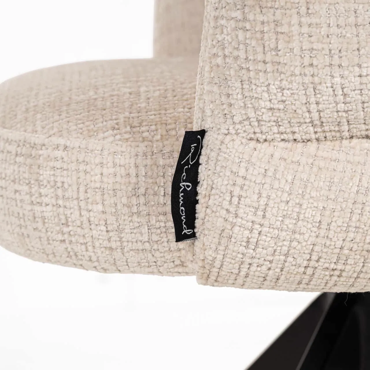 Detail van de eetkamerstoel Serenity niagara beige swivel fire retardant, met focus op het beige weefsel en het zwarte Richmond Interiors label