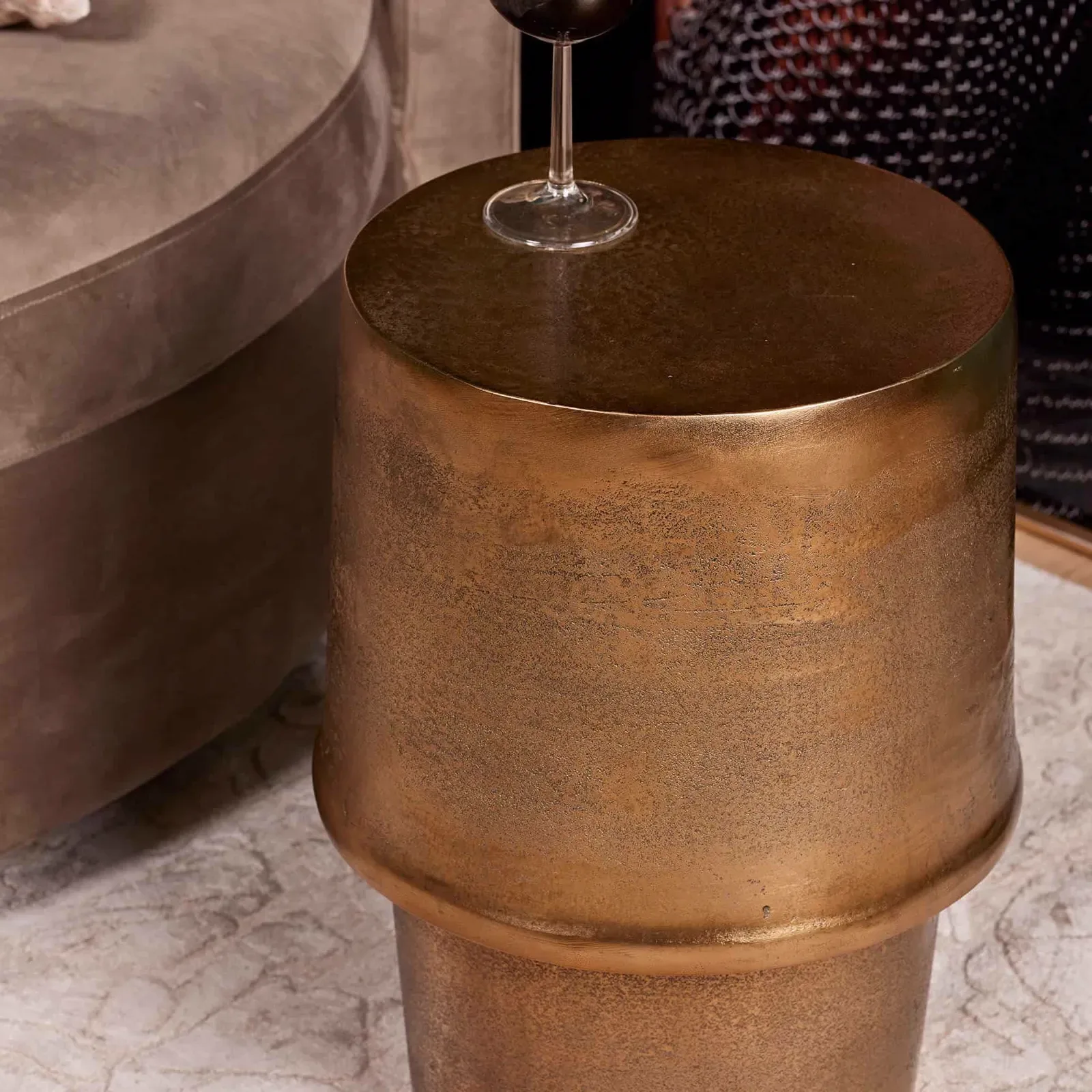 Detailaufnahme des Beistelltisch Glamor Gold Aluminium 30 cm mit einem Weinglas darauf, neben einem Sofa - Starfurn