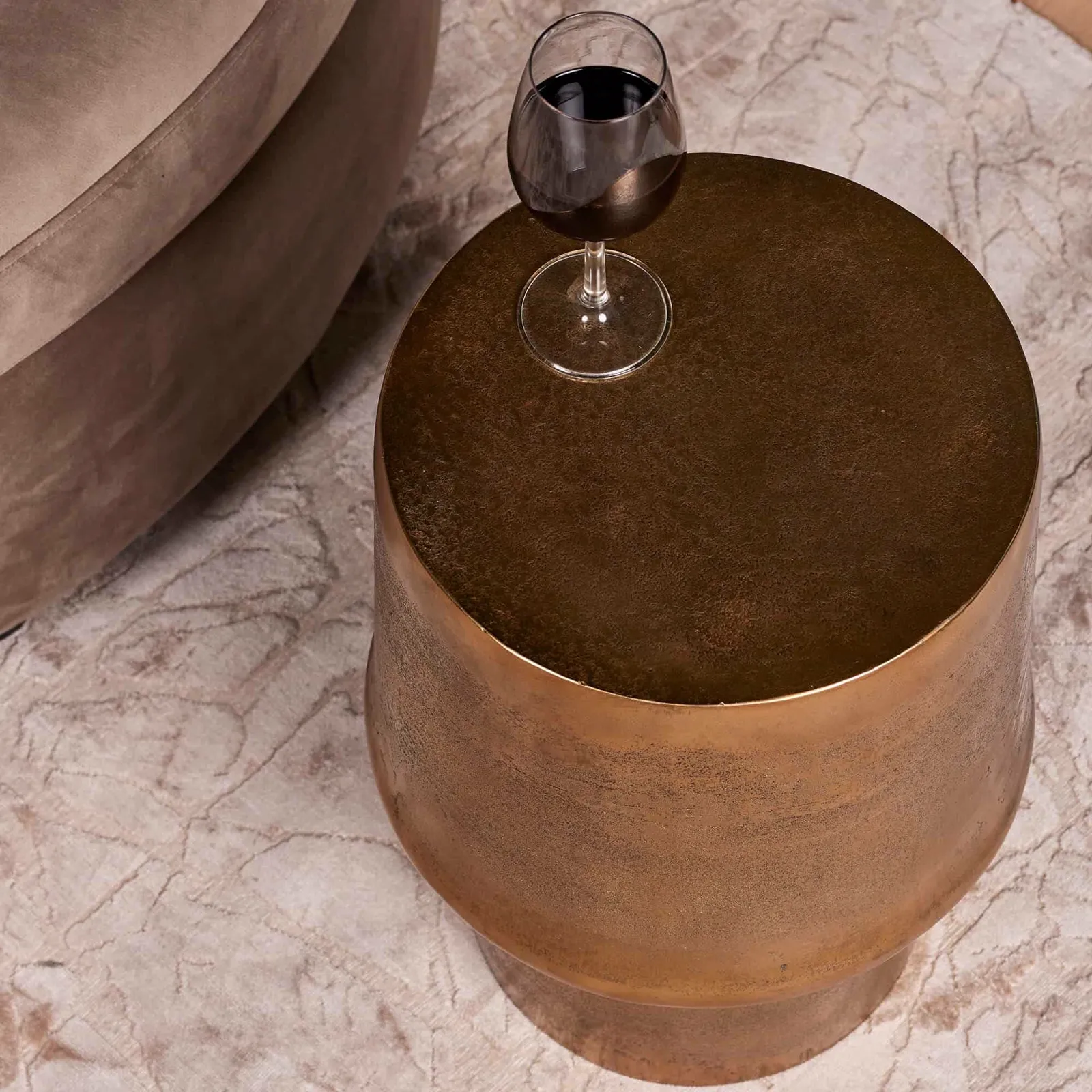 Draufsicht auf Beistelltisch Glamor Gold Aluminium 30 cm mit einem Glas Rotwein darauf, stehend auf einem hellen Teppich - Starfurn