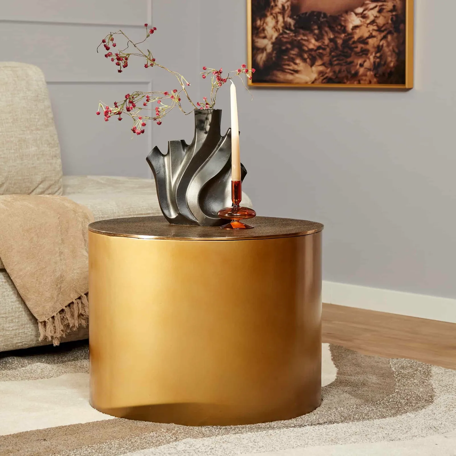 Couchtisch Fiore Gold in einem Wohnzimmer, mit einer Vase mit roten Zweigen und einer Kerze - Starfurn