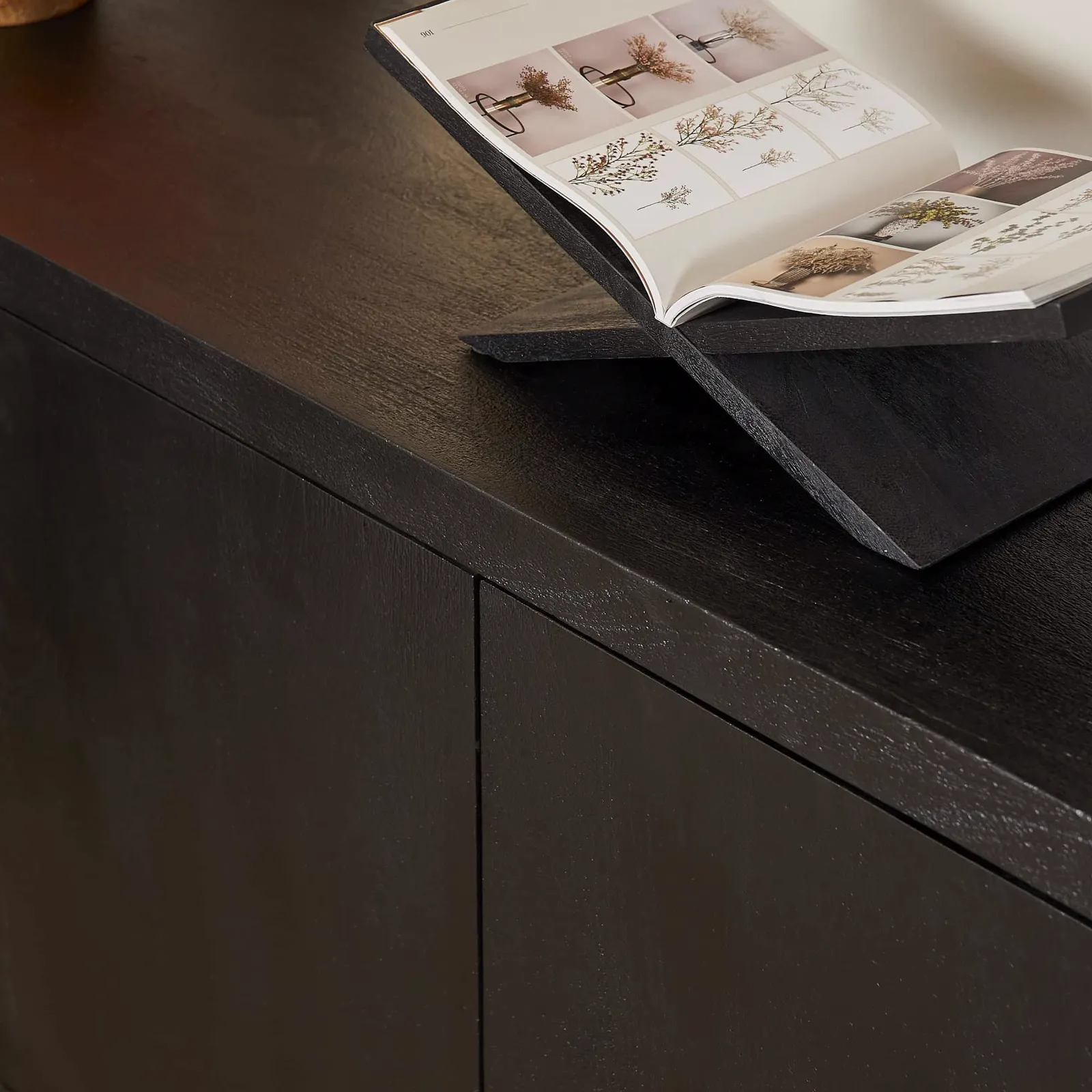 Nahaufnahme des Sideboard Brüssel Schwarz Mangoholz 200 cm mit einem offenen Buch auf einem Ständer darauf - Starfurn