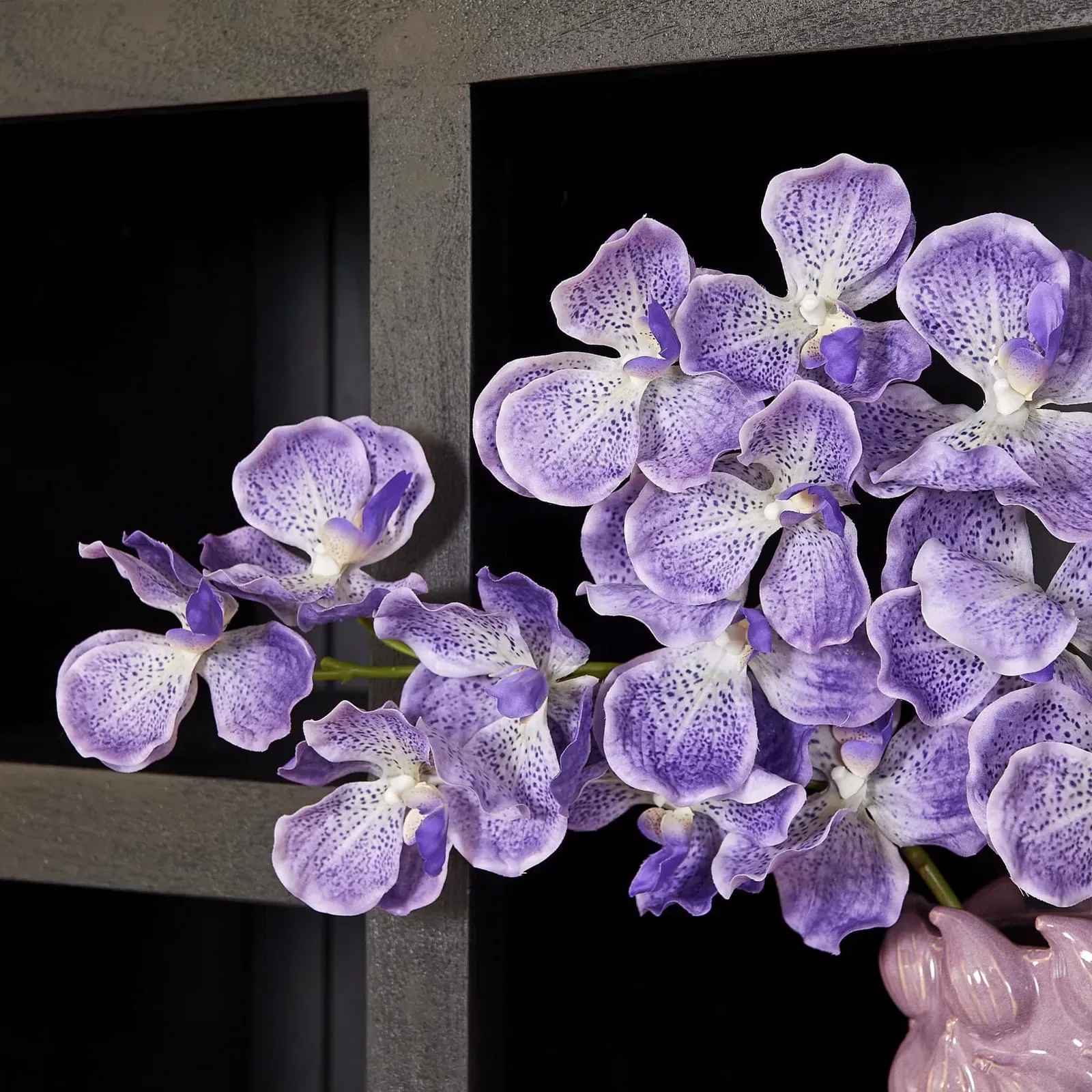 Nahaufnahme von lila Orchideen in einer Vase, mit dem Regalsystem Brüssel Black im Hintergrund - Starfurn