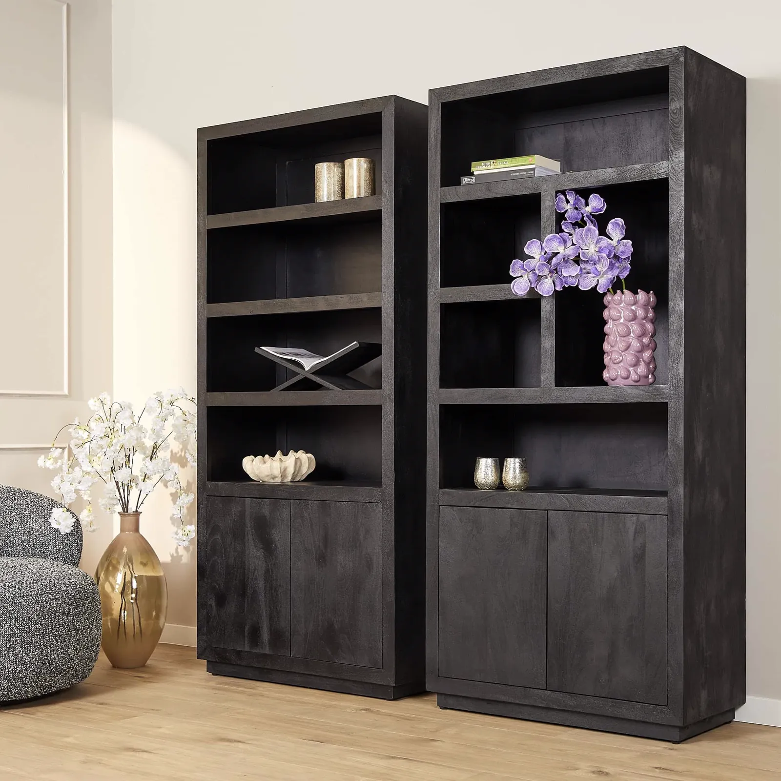 Zwei schwarze Regalsysteme Brüssel Black in einem hellen Wohnzimmer mit Dekoration und einem Sessel - Starfurn