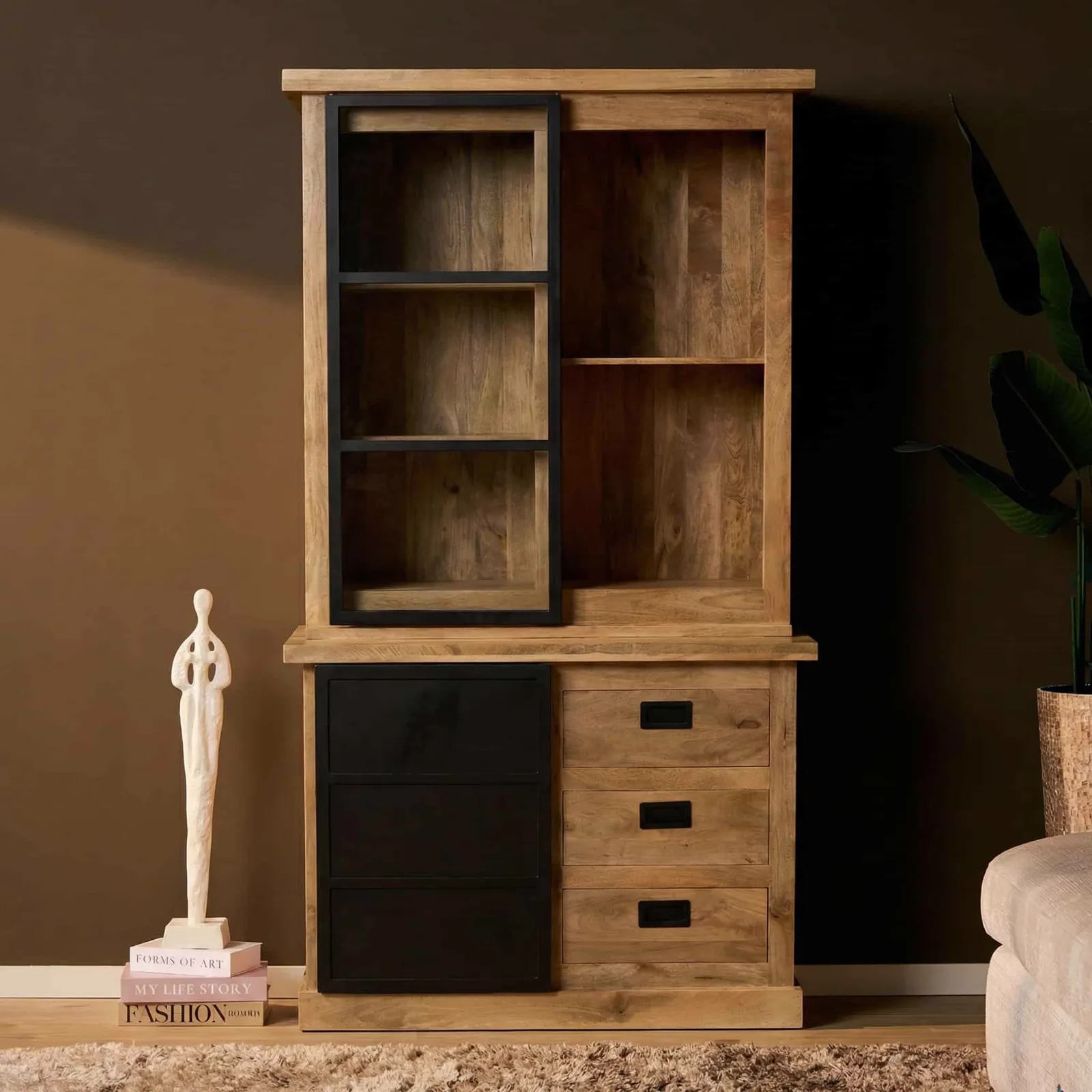 Vitrinekast Noa Naturel Mangoholz 120 cm in einer stimmungsvollen Studio-Umgebung mit Pflanze und Dekoration - Starfurn
