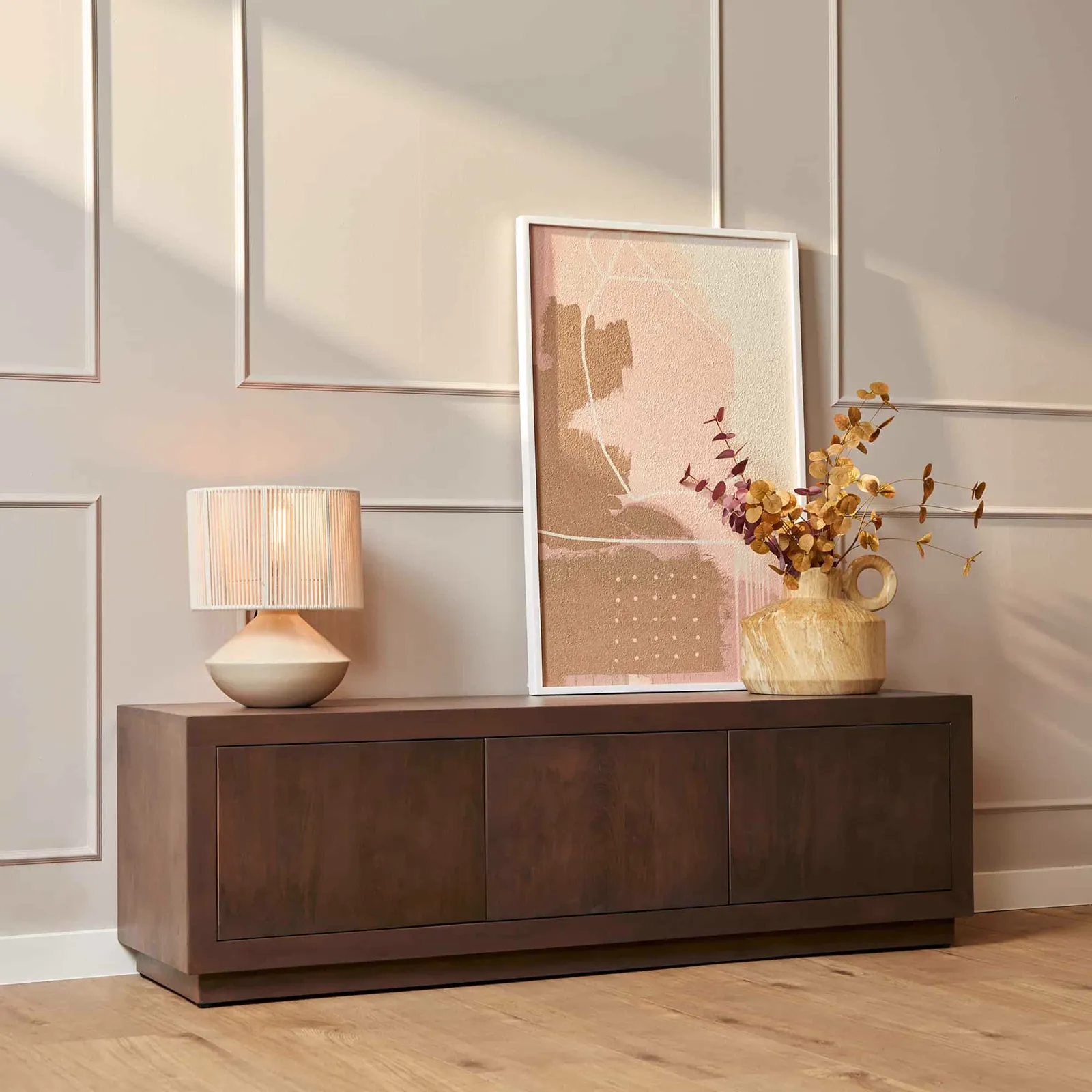 Salontafel Brussel Walnut in een sfeervolle setting met een lamp, kunstwerk en vaas met takken - Starfurn