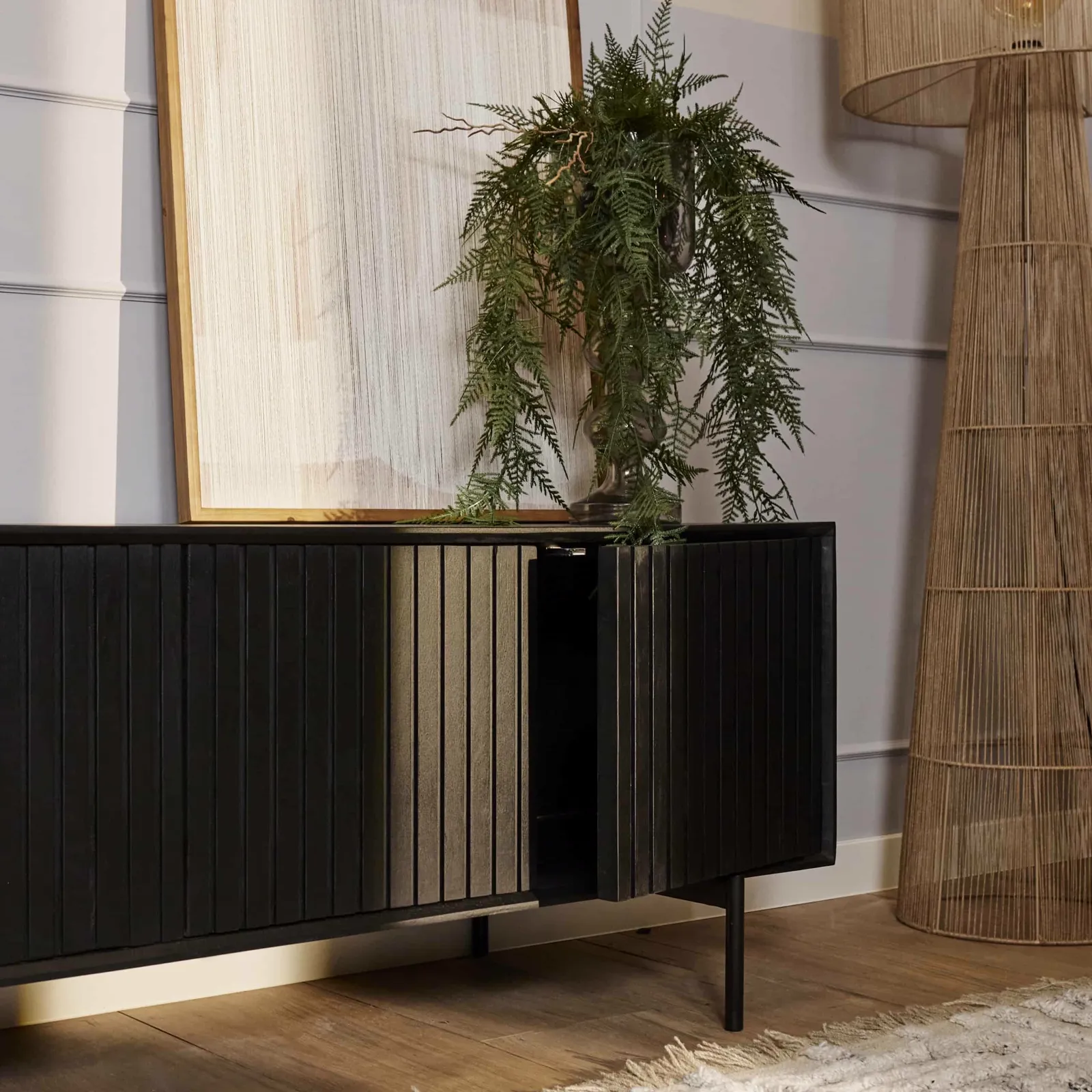 TV-Möbel Madison Black in einem Wohnzimmerambiente mit einer Pflanze und einer Rattanlampe - Starfurn