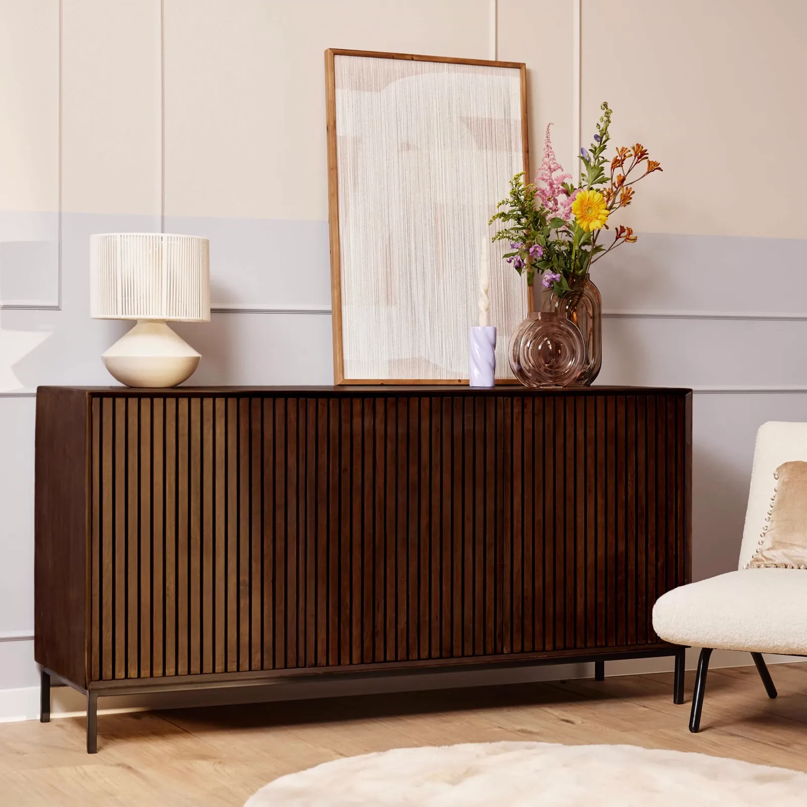 Sideboard Madison Braun Mangoholz 165 cm in einem Wohnzimmer mit Dekoration und einem Sessel - Starfurn