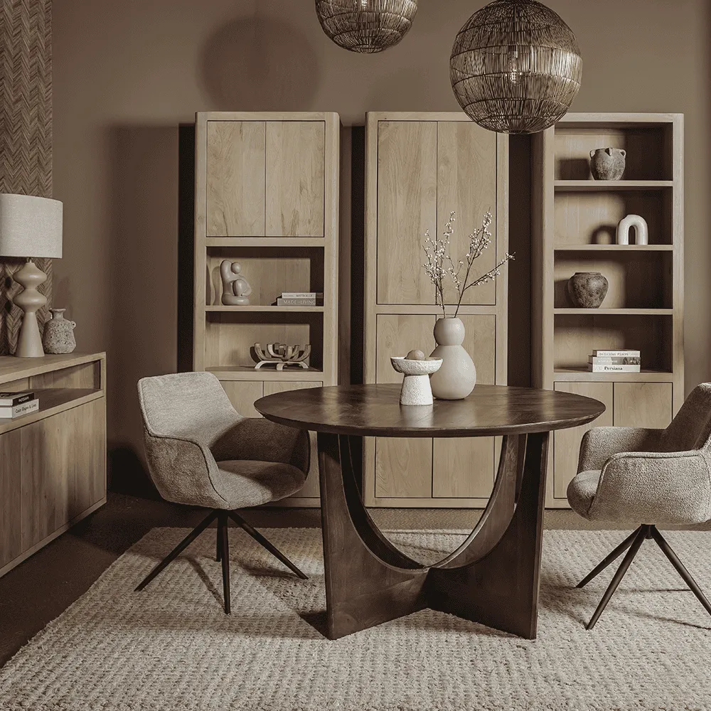 Der Fondo Armstuhl aus Stoff Mona 120 Taupe, drehbar, steht an einem runden Esstisch in einem stimmungsvollen Wohnzimmer - Tower Living