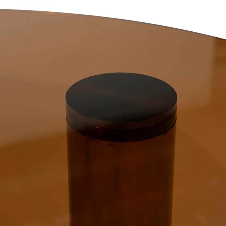Detailaufnahme des Couchtisch Aero Glas & Resin Braun, mit Fokus auf das dunkle, runde Bein und die Glasplatte - By-Boo