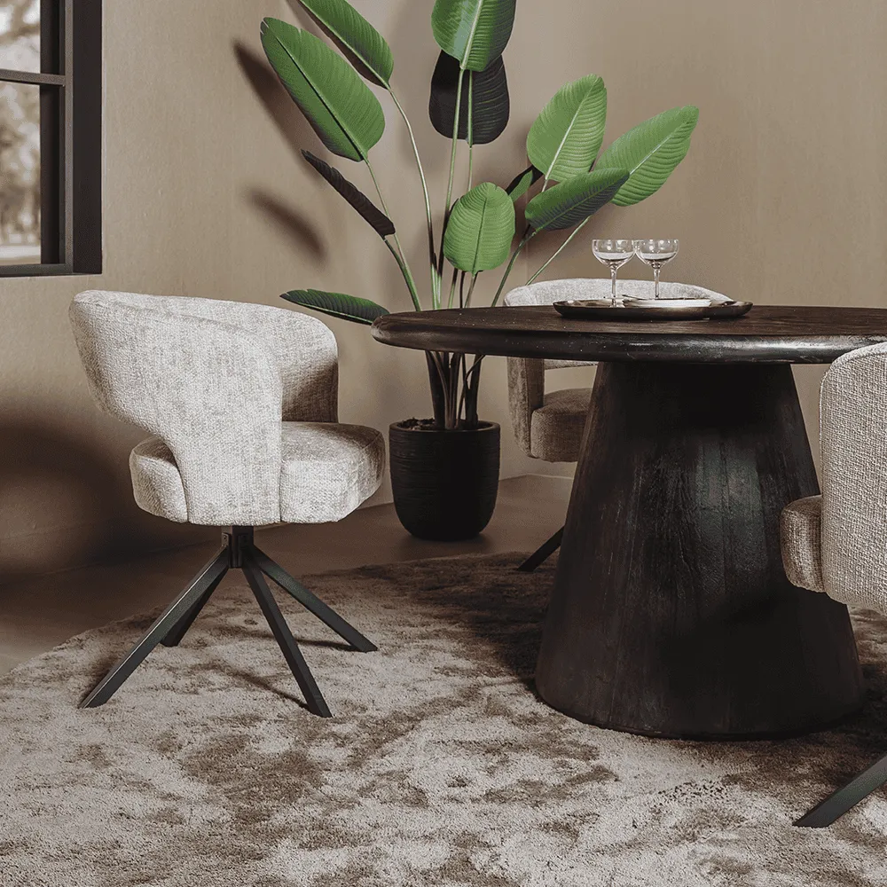 Der Asti Esstisch rund schwarz 130 cm in einem stimmungsvollen Ambiente mit Stühlen und Pflanze - Tower Living