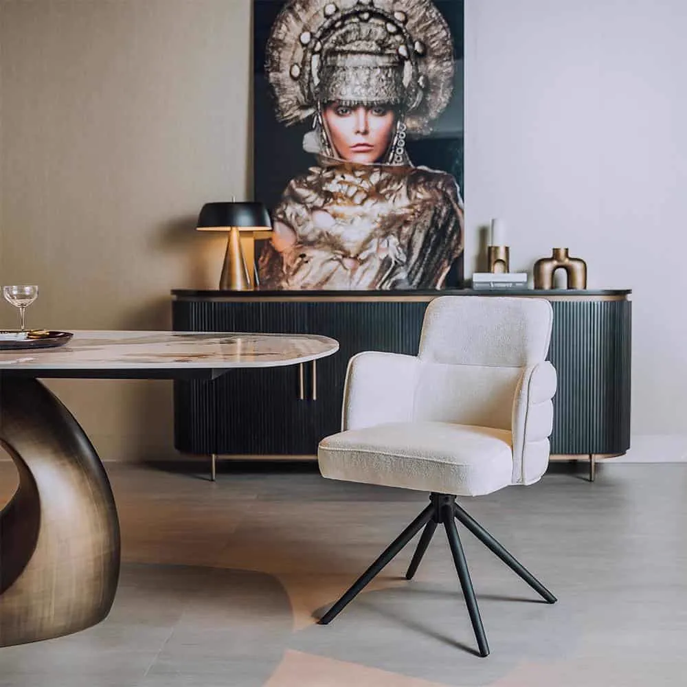 Der Rumo Armlehnstuhl aus ecrufarbenem Stoff in einem modernen Interieur mit ovalem Tisch und Sideboard - Tower Living