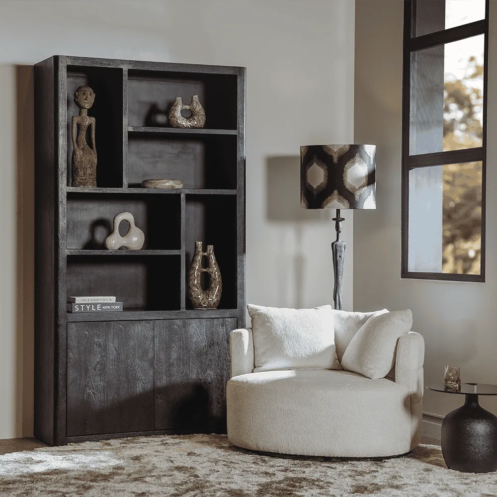 Der Bolza Sessel - Trenza 6 ivory (drehbar) in einem Wohnzimmer mit einem dunklen Bücherregal und Teppich - Tower Living