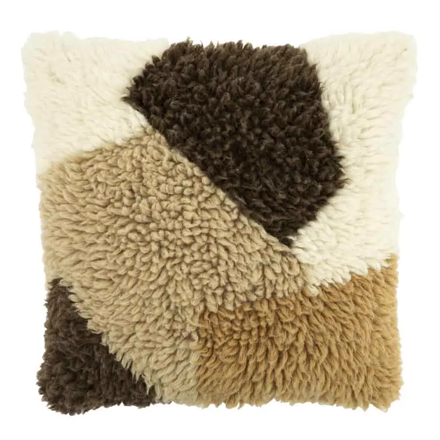 Kissen Navaro mit einer weichen, zotteligen Textur und Farbflächen in Braun, Beige und Creme auf weißem Hintergrund - By-Boo