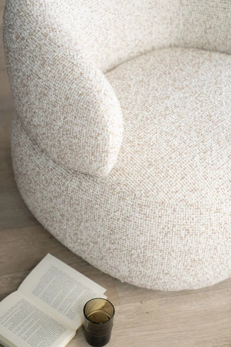 Nahaufnahme des Sessels Maeve - beige Maywood mit einem Buch und Glas auf dem Holzboden - Eleonora