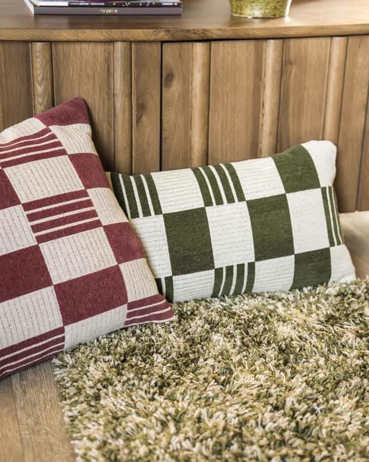 Das Kissen Twist 35x55 cm - grün und ein rotes Kissen auf einem grünen Shaggy-Teppich - By-Boo