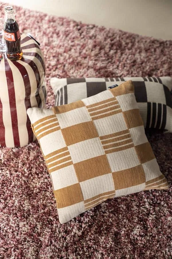 Zwei Kissen Twist 45x45 cm - Senf und ein dunkleres Kissen auf einem rosa Shaggy-Teppich - By-Boo