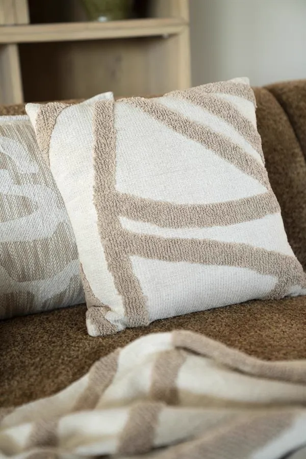 Zwei Kissen Majani Taupe mit abstraktem Muster auf einer braunen Couch, mit einem Plaid im Vordergrund - By-Boo