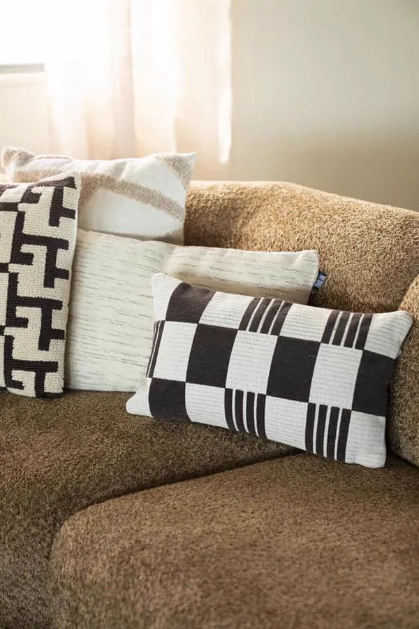 Kissen Twist 35x55 cm - braun liegt auf einem braunen Sofa zwischen verschiedenen Kissen - By-Boo