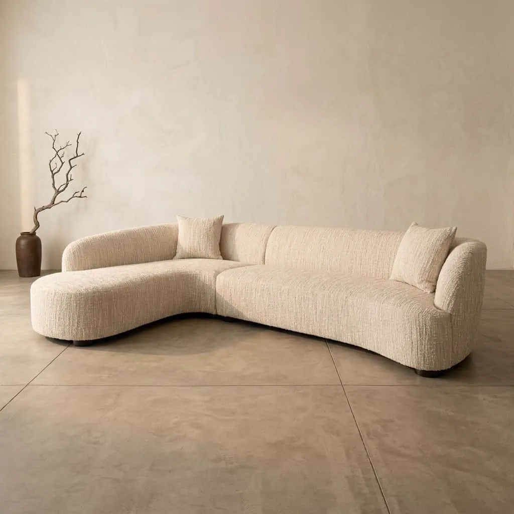 Sofa Pandora beige Angora Lounge Left in einem hellen Studio mit einer Vase und einem Ast neben dem Sofa - Richmond Interiors