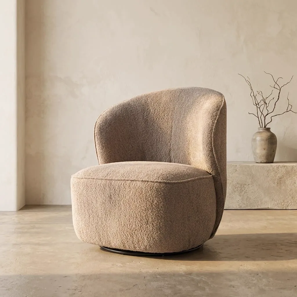 Der drehbare Belvi Sessel in altrosafarbenem Stoff steht in einem minimalistischen Studio mit einer Vase mit Ästen - Tower Living
