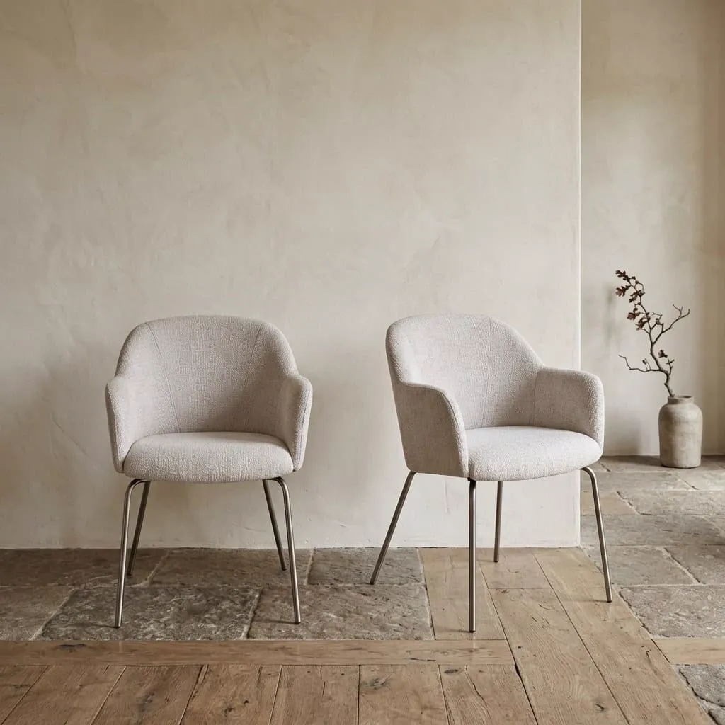 Twee eetkamerstoelen 460 met een lichtgrijze stoffen bekleding en metalen poten in een interieur - Koopmans Meubelen