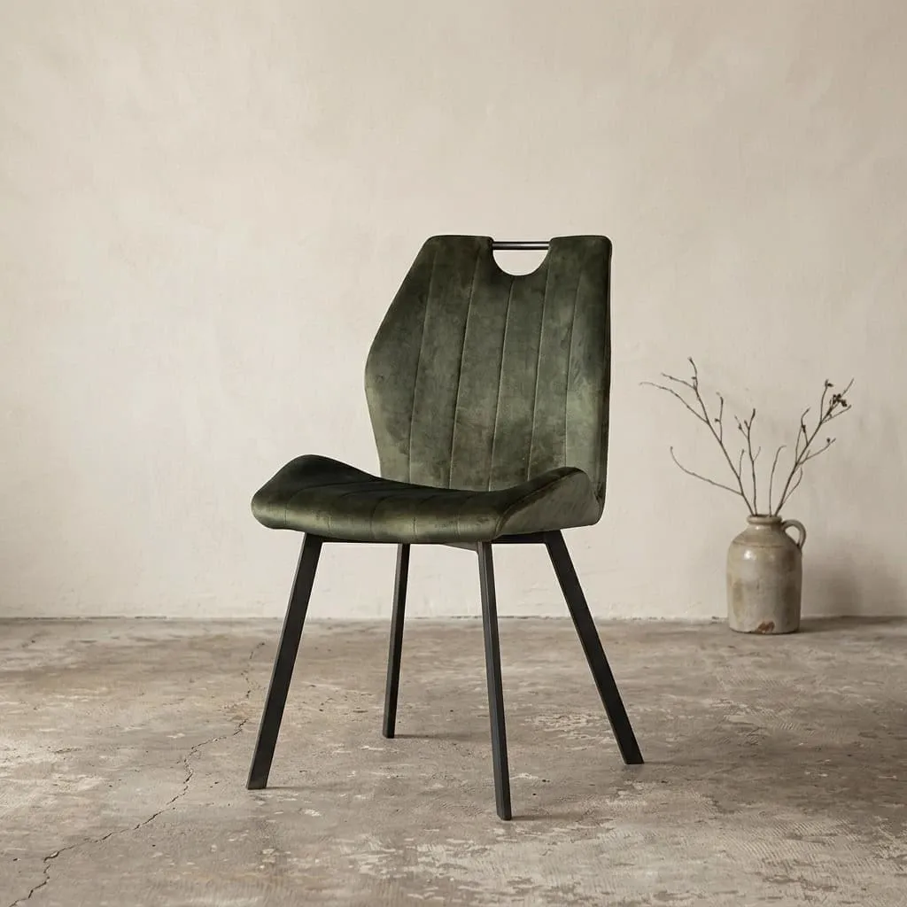 Esszimmerstuhl Devon - Velvet Hunter in einem Studio mit heller Wand und Betonboden, schräg von vorne fotografiert - Lenselink Furniture