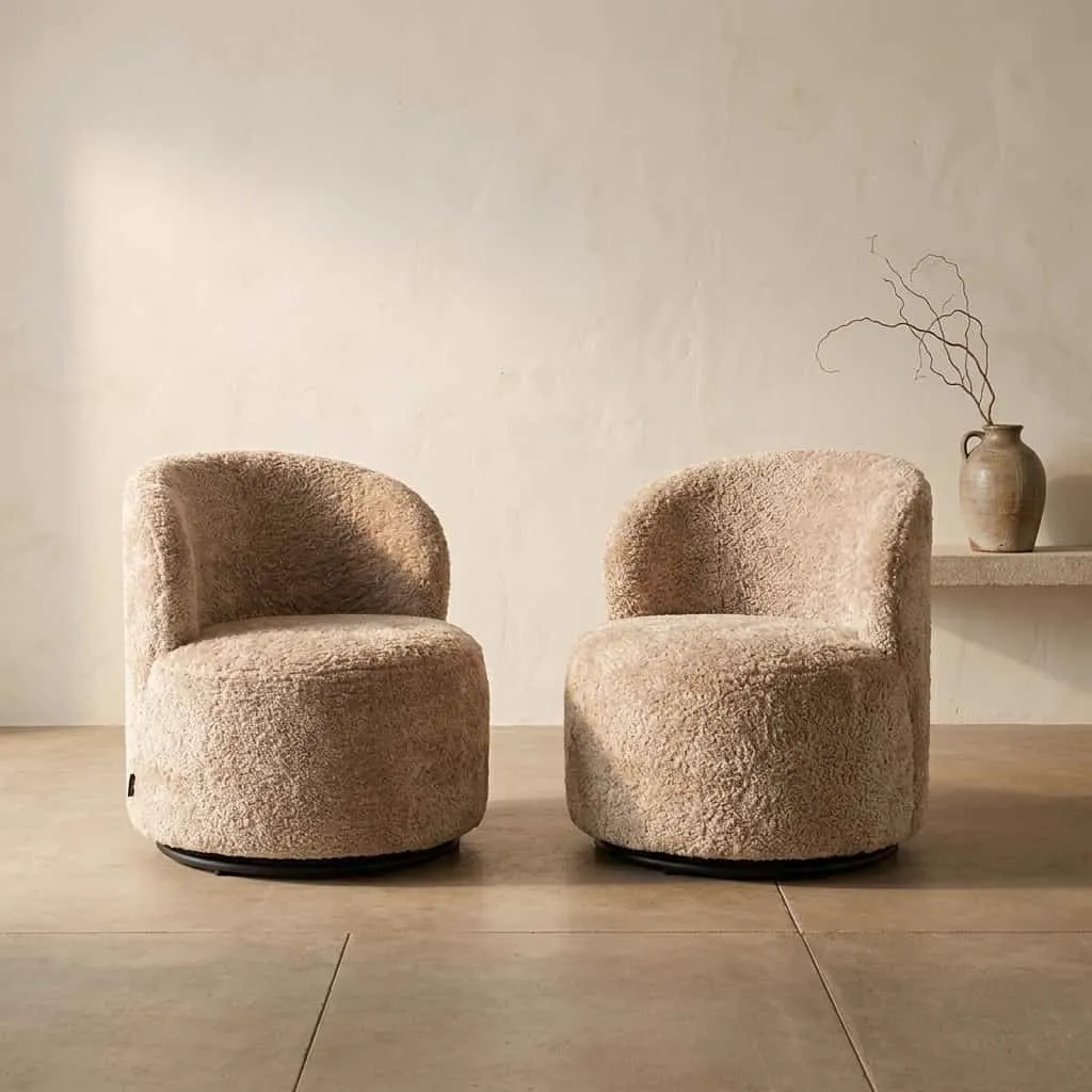 Twee Jackie sheep natural swivel kids loungestoelen in een lichte studio met een vaas en takken op een plank - Richmond Interiors